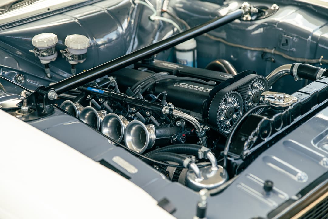 Polished intake trumpets and throttle bodies in a classic car engine bay