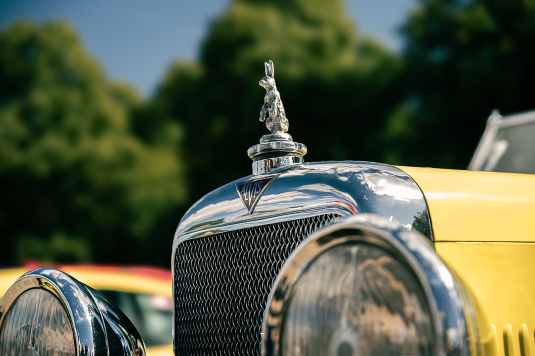 Leaping mascot above the chrome radiator grille of a yellow vintage car