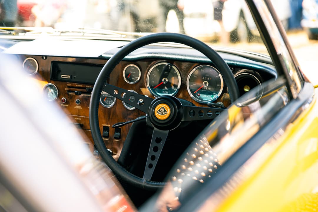 Lotus steering wheel and wooden dashboard inside a yellow classic sports car