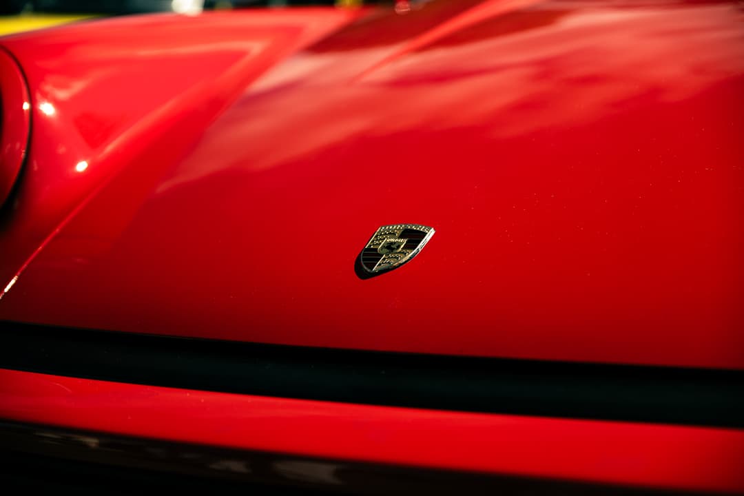 Gold shield badge on the red bonnet of a classic sports car