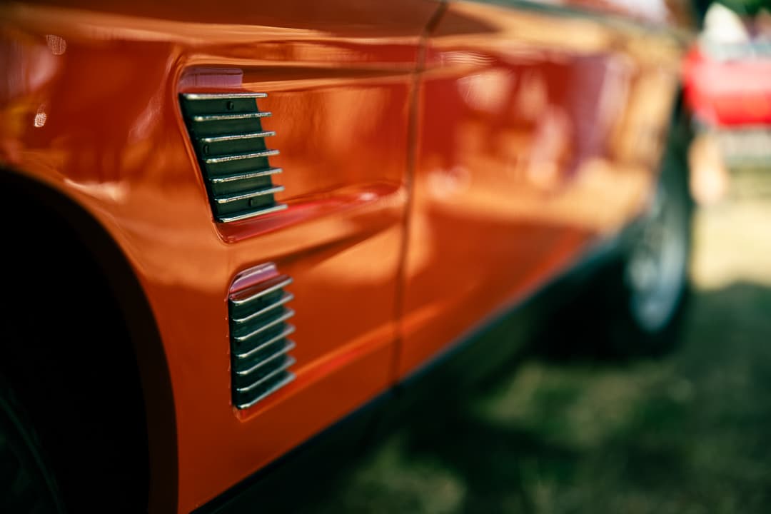 Chrome side vents along the flank of an orange classic sports car