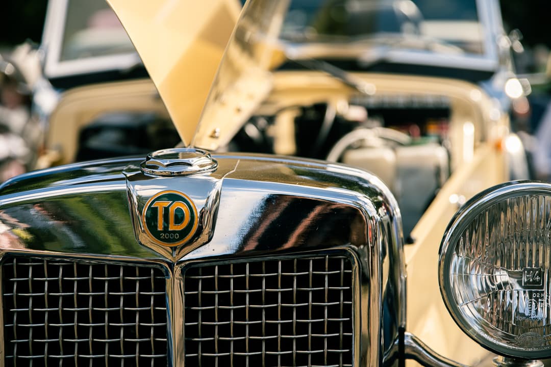 Chrome grille and badge on a cream pre-war tourer with its bonnet raised