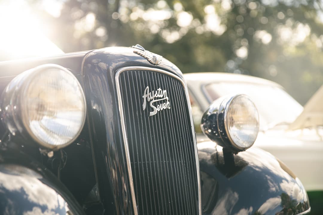 Austin Seven badge and headlamps backlit by low sun