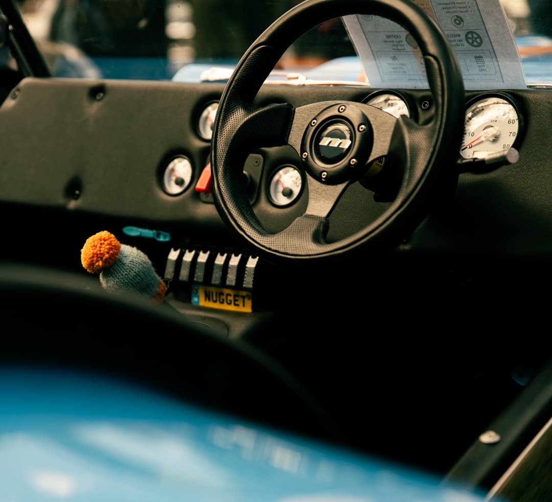 Steering wheel and toggle switches in the cockpit of a blue lightweight sports car