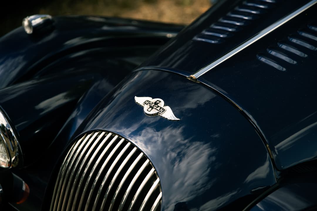 Winged Morgan badge and chrome grille on a dark blue Morgan