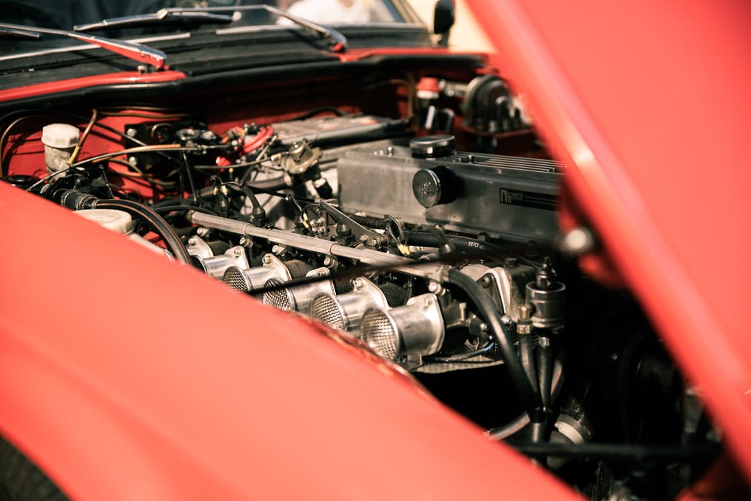 Straight-six engine under the raised bonnet of a red classic sports car