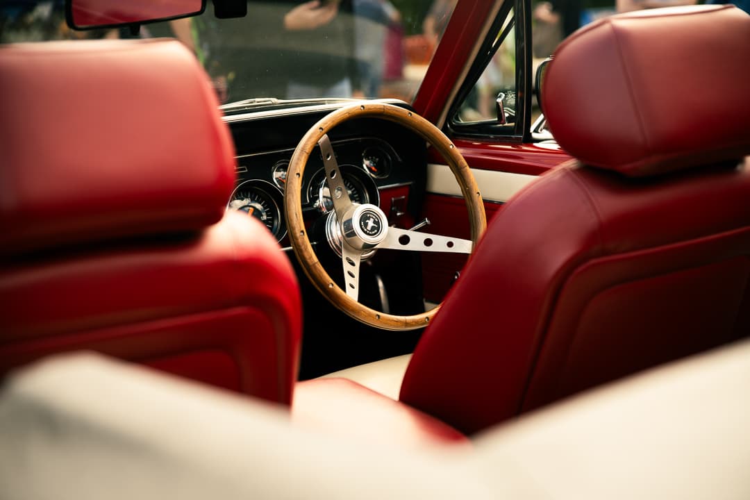 Wood-rimmed steering wheel and red leather seats in a Ford Mustang convertible