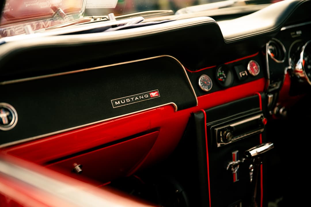 Mustang badge on the black and red dashboard of a classic Ford Mustang