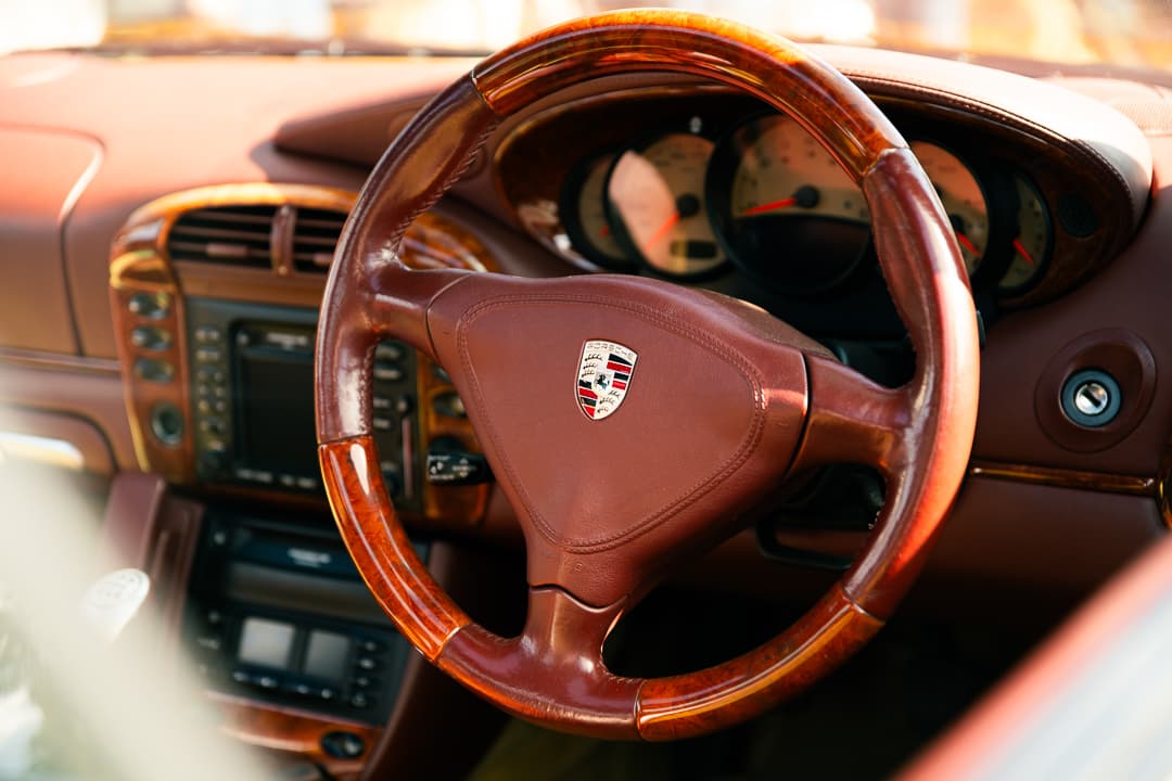 Wood-rimmed Porsche steering wheel in a terracotta leather interior