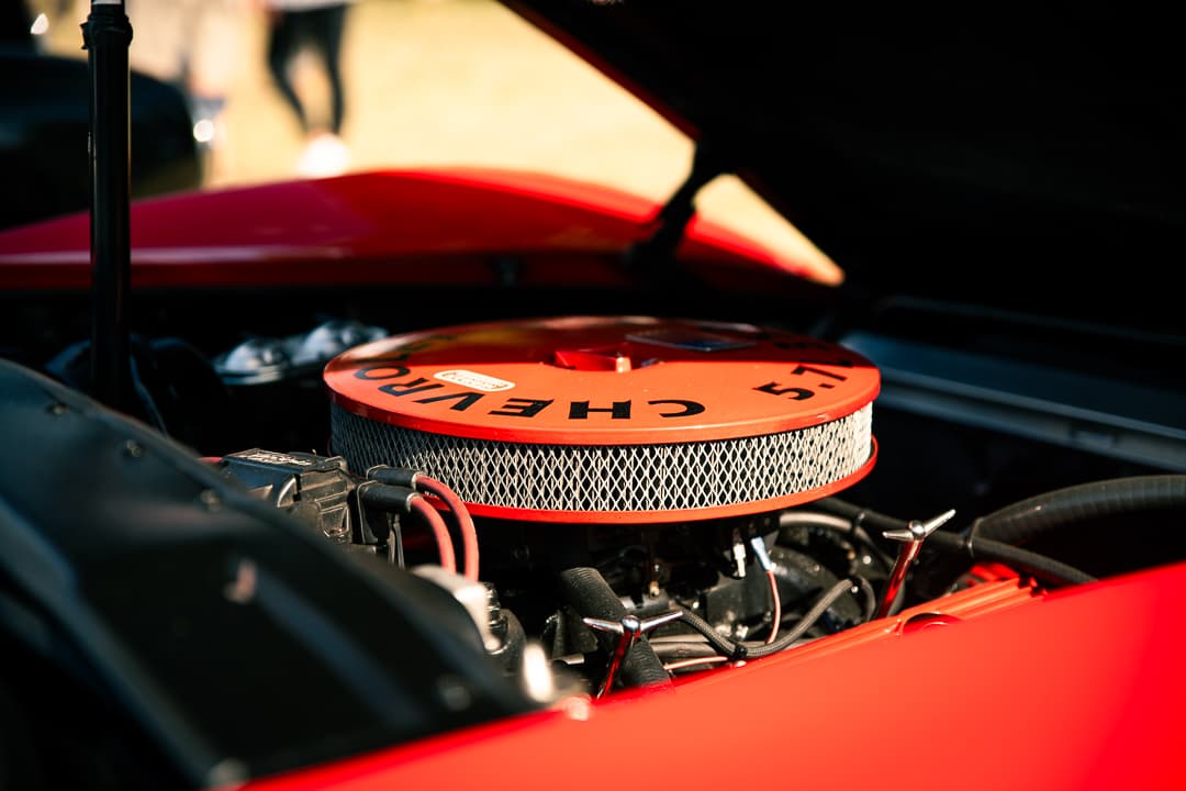 Chrome Chevrolet air cleaner in the engine bay of a red classic car