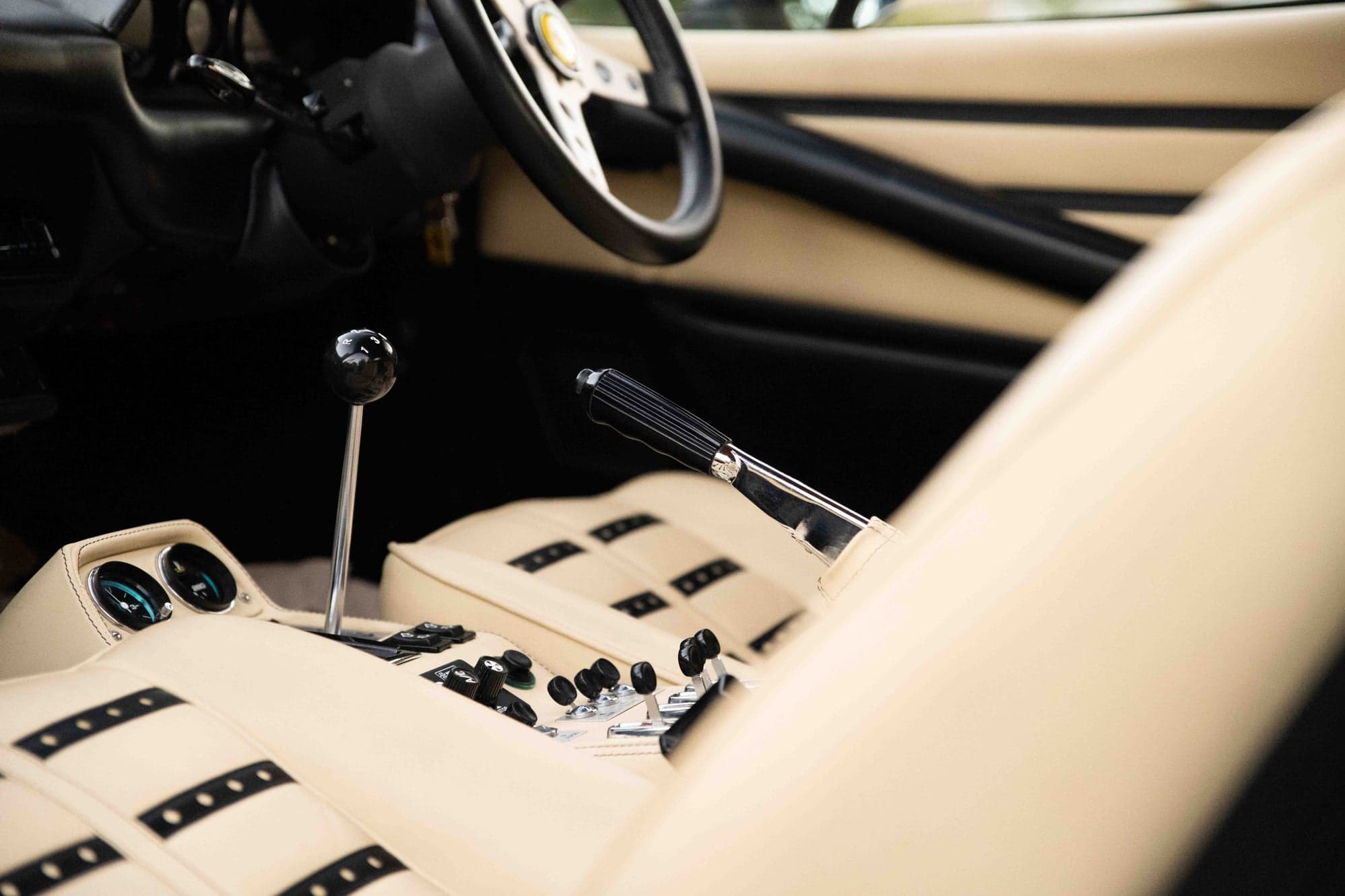 Cream leather interior of a Ferrari 308 with its chrome gear lever and handbrake