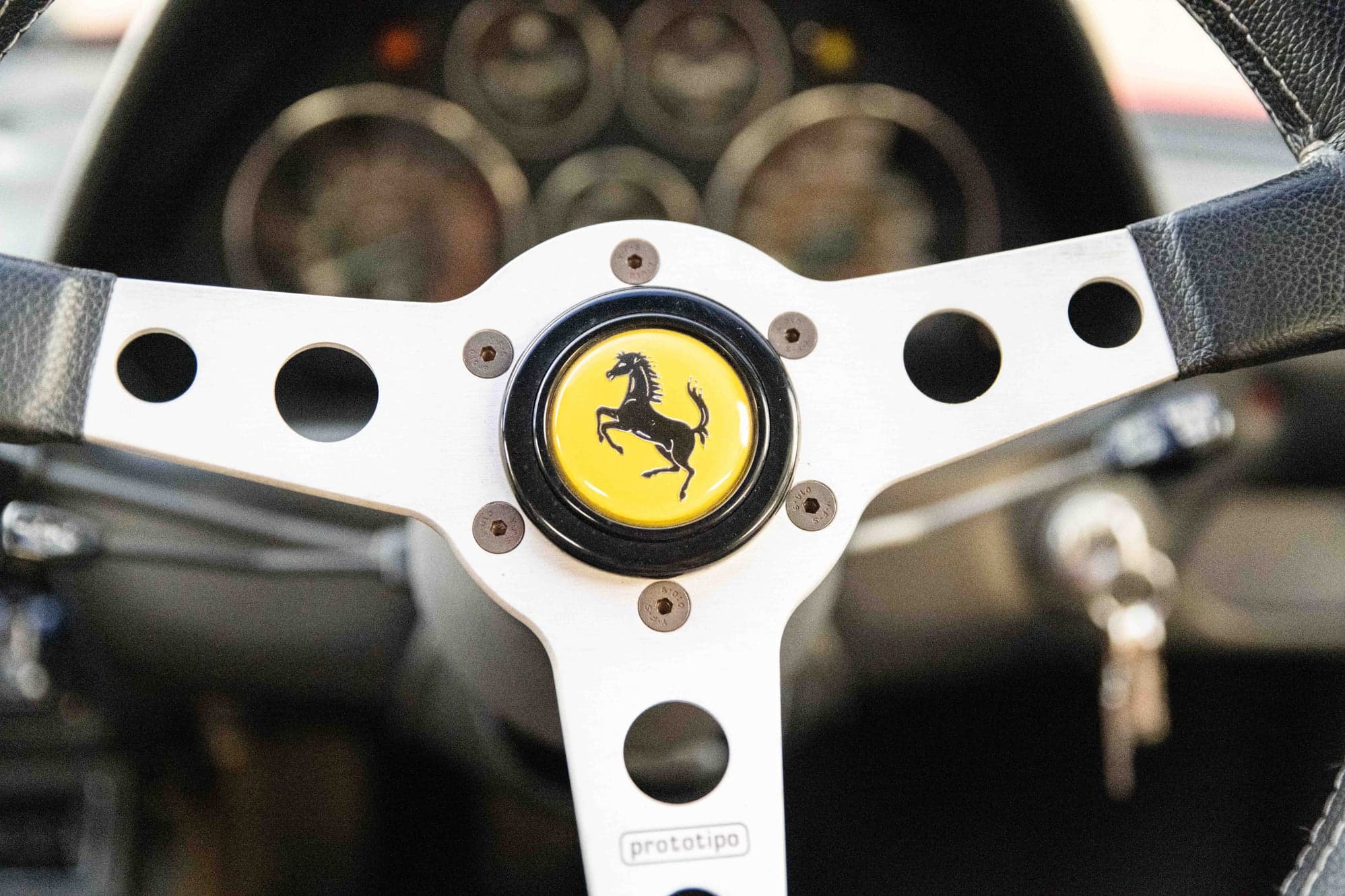 Prancing horse badge at the centre of a Ferrari 308's drilled steering wheel