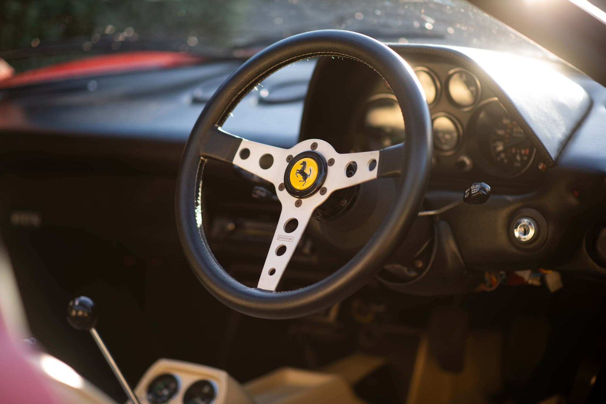 Ferrari 308 steering wheel and dashboard dials lit by low sun