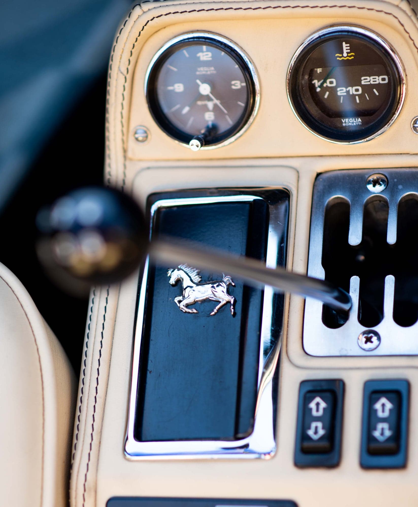 Prancing horse on the gear gate below the clock and temperature gauge of a Ferrari 308
