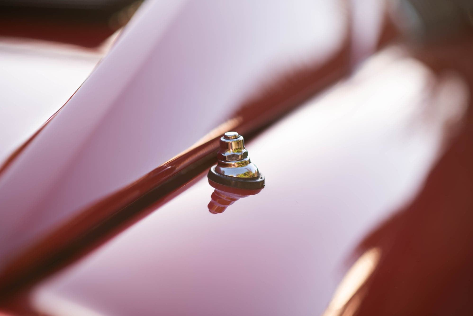 Chrome bonnet catch standing proud of a red Ferrari's bodywork