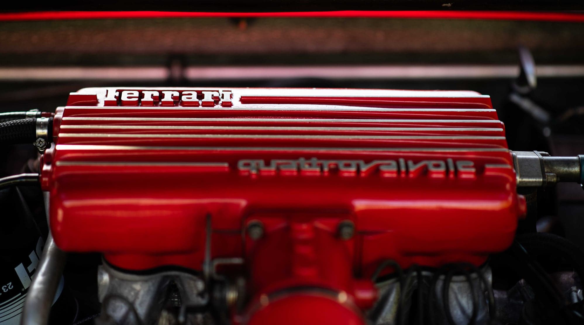 Red Ferrari quattrovalvole cam cover in the engine bay of a 308