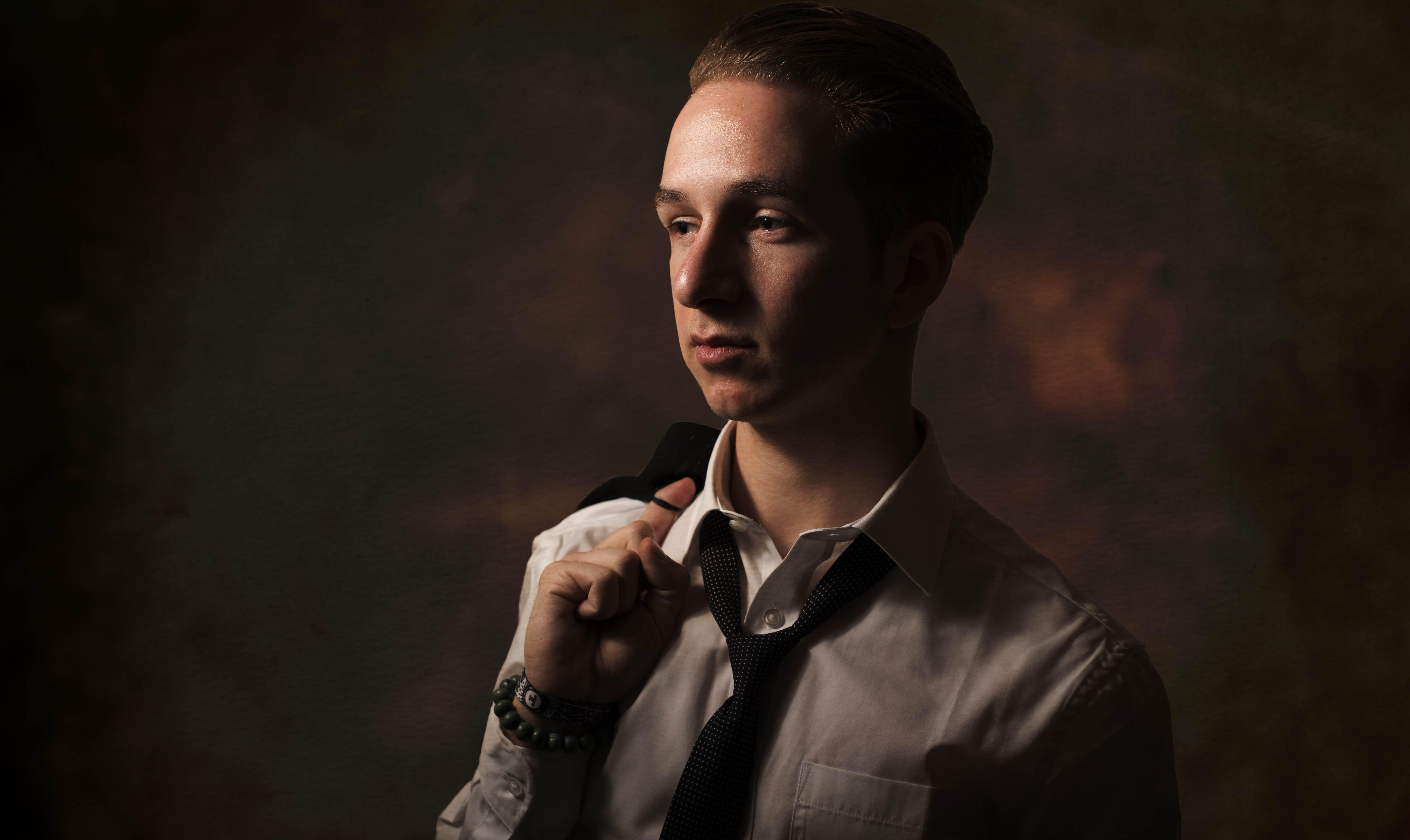 Moody studio portrait of a young man in a white shirt and loosened tie