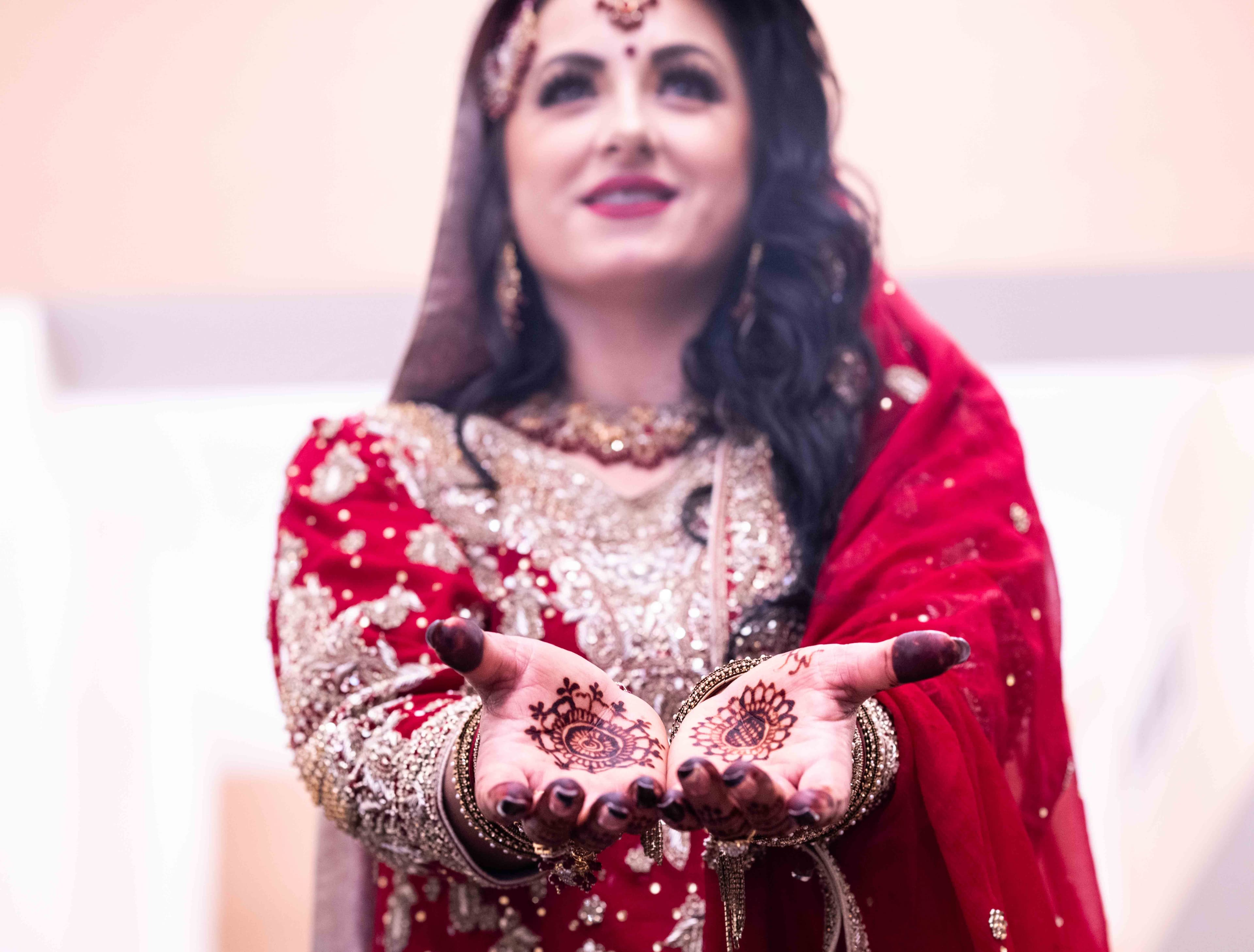 A bride displays her hands covered in detailed henna designs