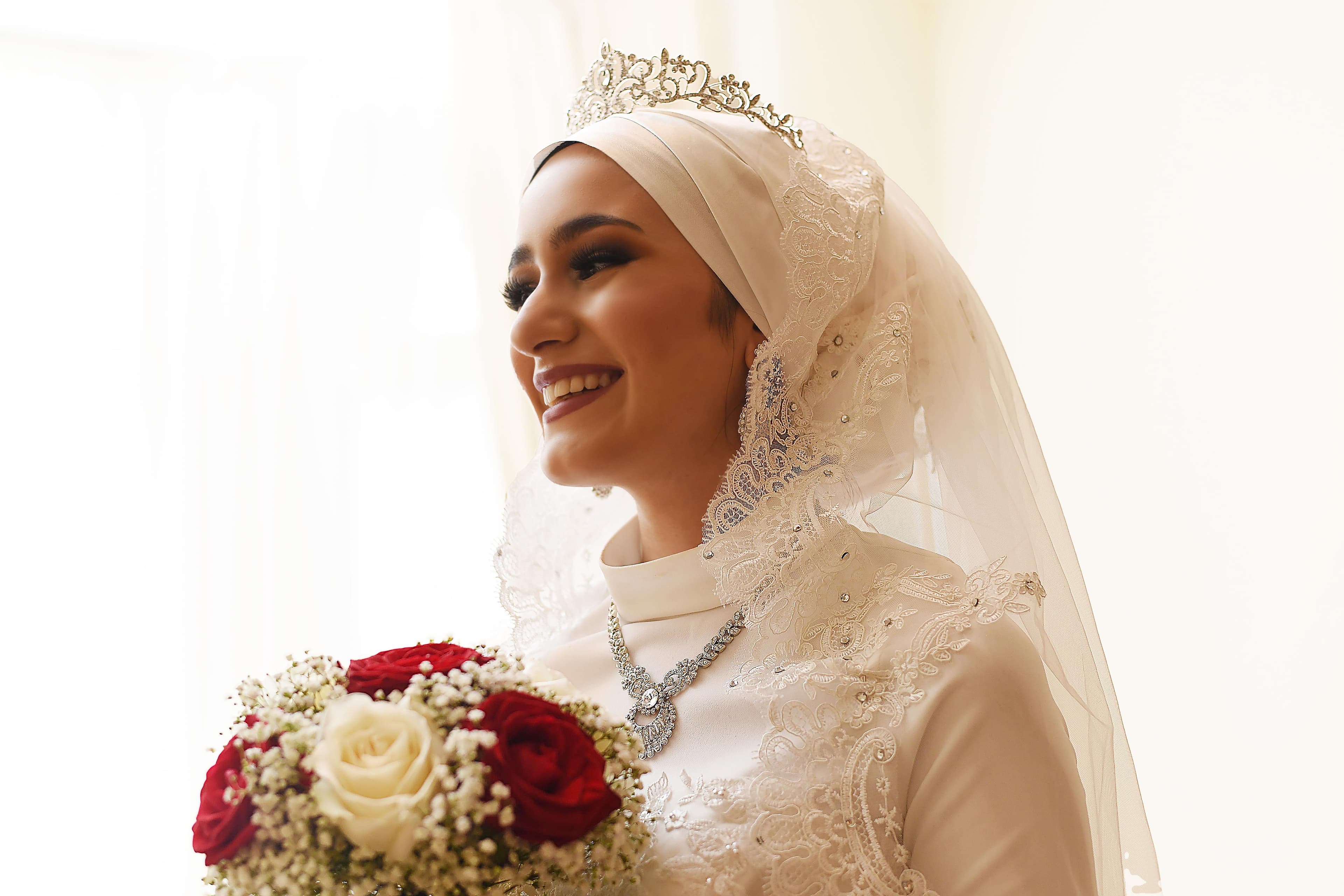 Bride smiling with bouquet in illuminated room