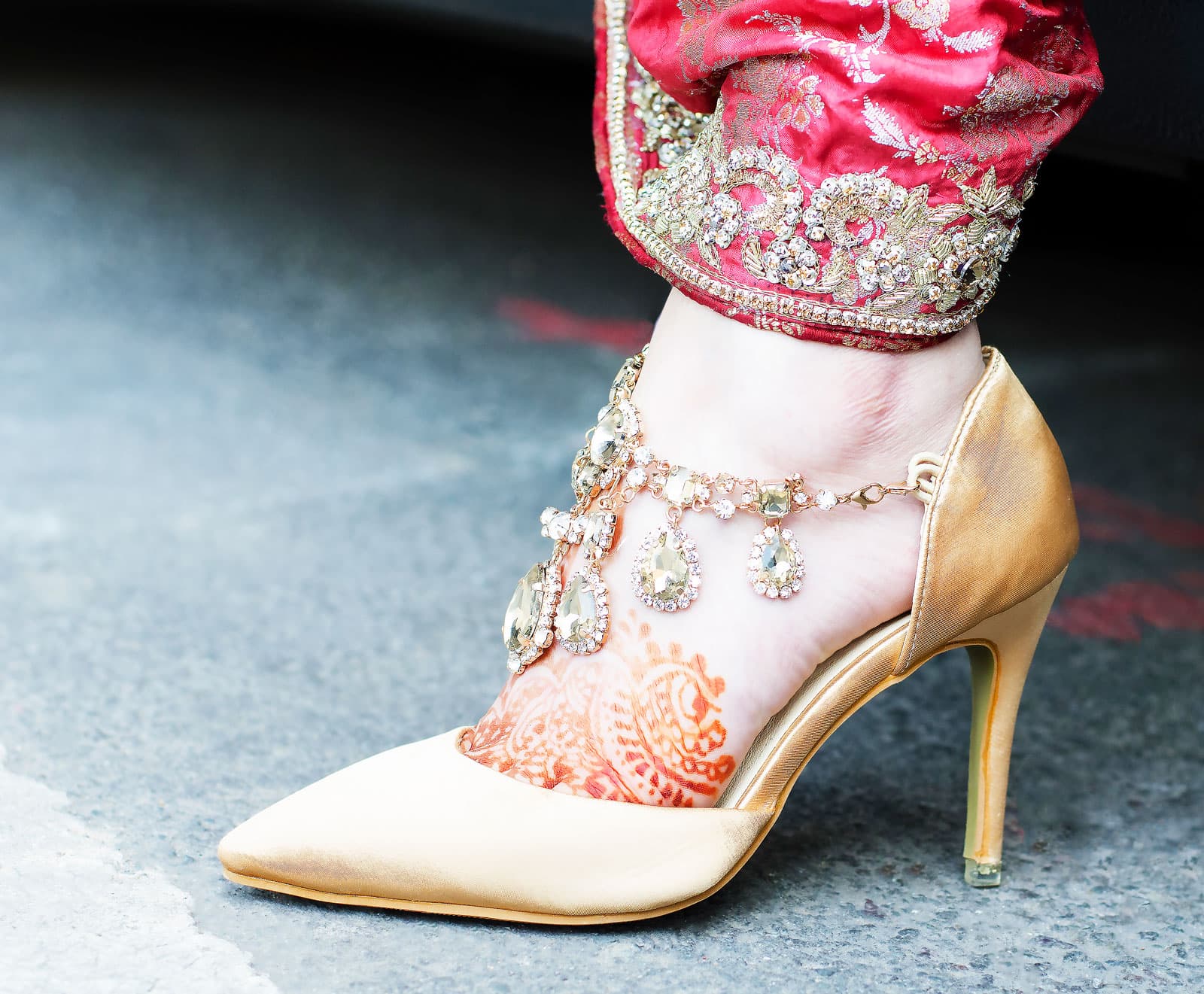Bride's ankle with traditional Asian anklets, alighting from the car
