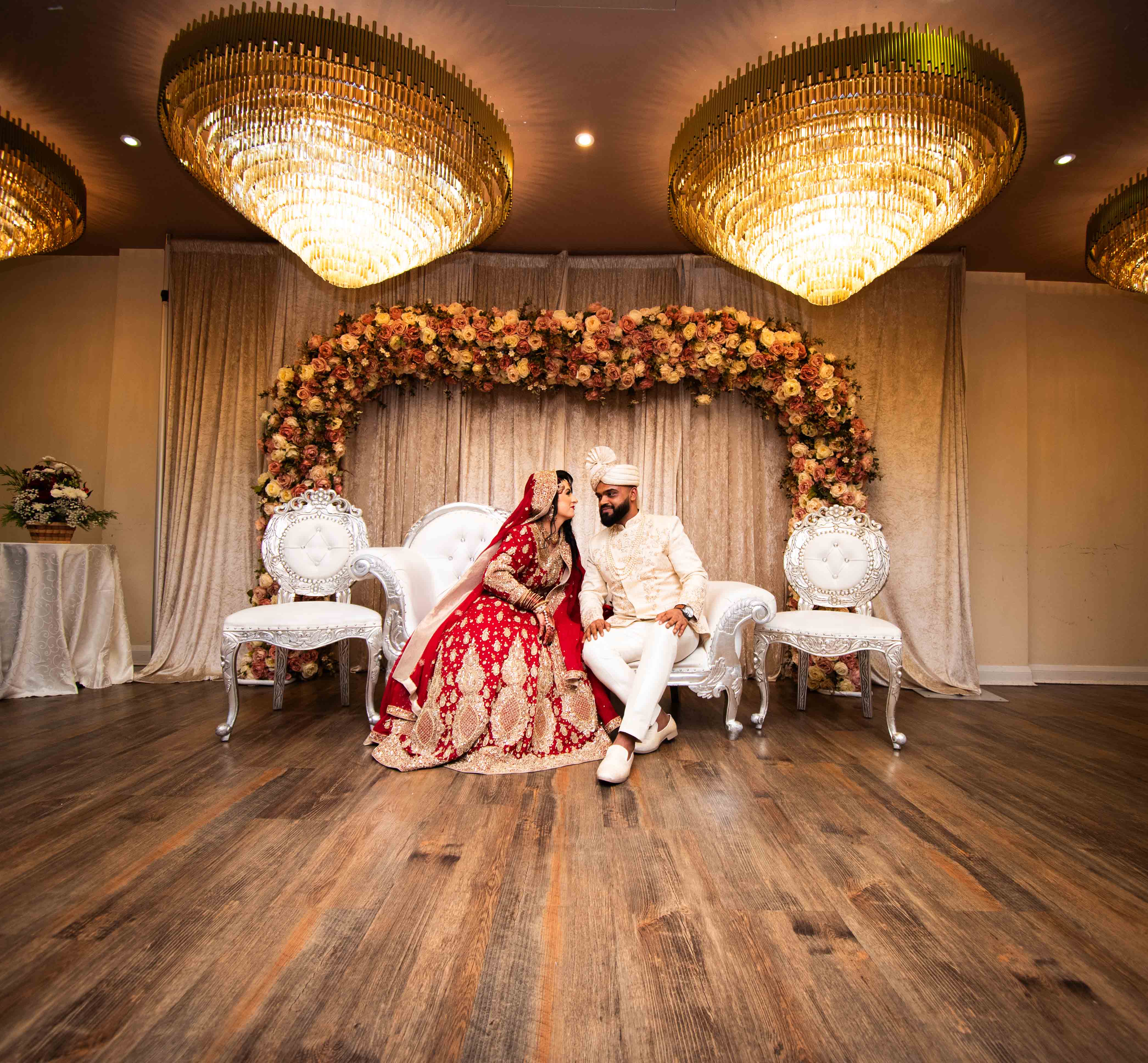 The bride and groom sitting regally on an ornately designed wedding throne