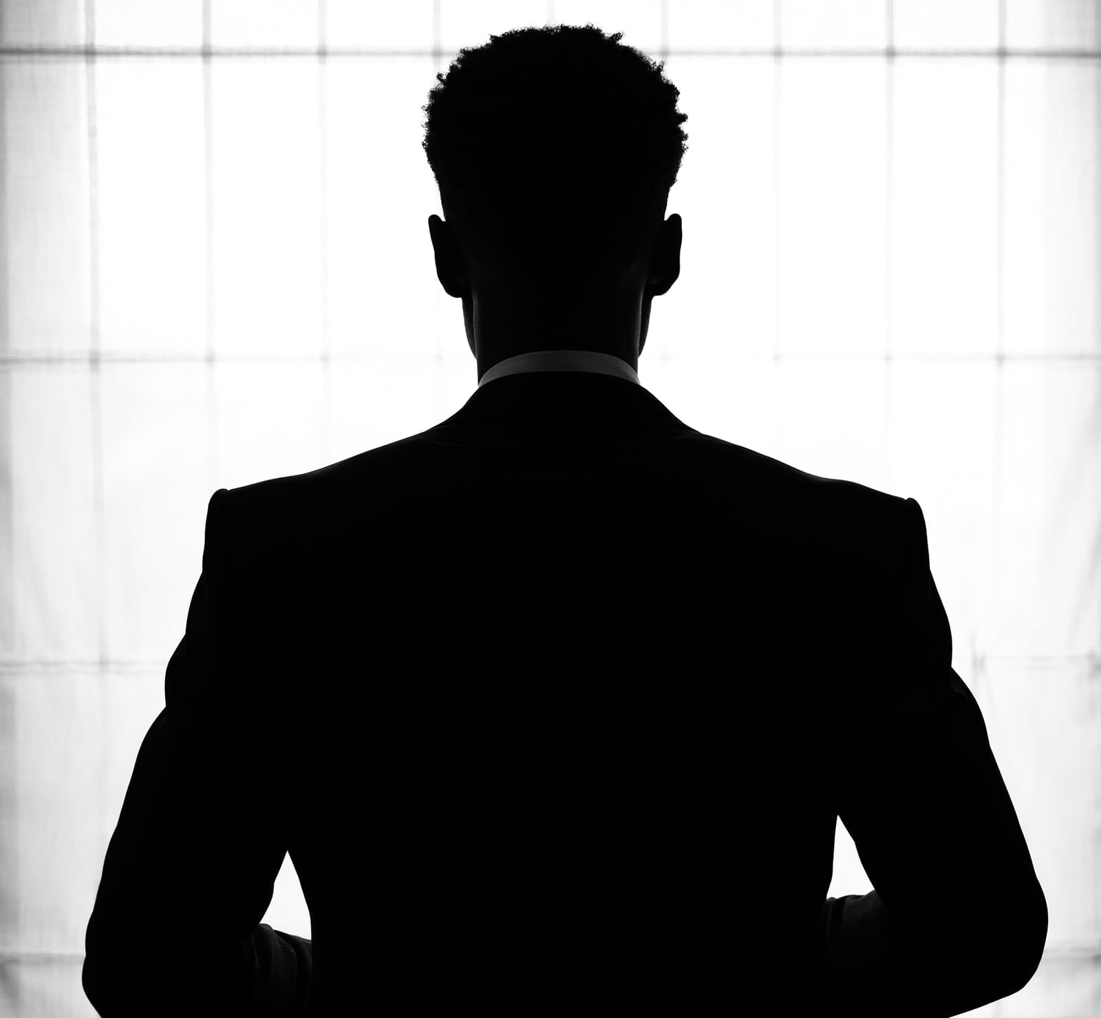 The groom getting ready in the soft light of a hotel window
